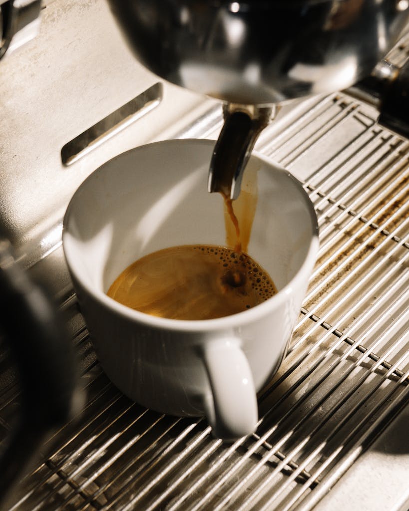 A close-up of espresso pouring from a machine into a cup, highlighting the rich aroma and fresh brew.