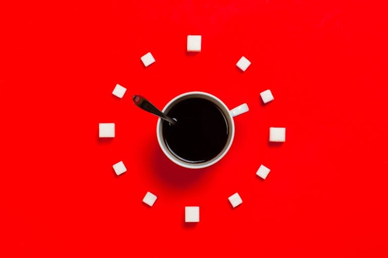 Artistic coffee composition with sugar cubes on a striking red background, from above.