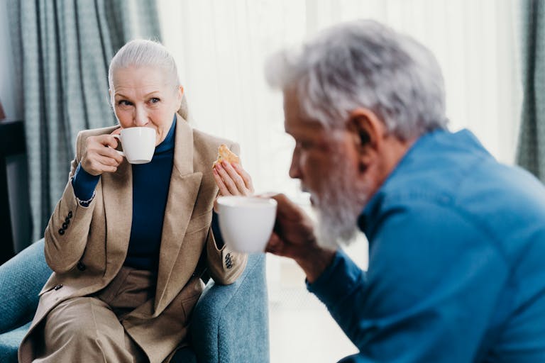 Senior couple enjoying coffee and conversation in a cozy indoor setting.